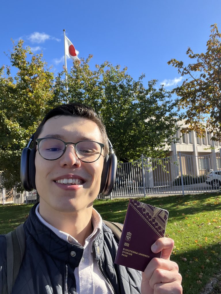 Foto på mig där jag håller upp mitt pass framför japanska ambassaden