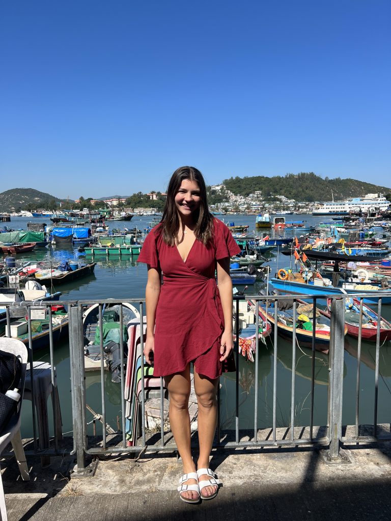 Girl in red dress standing in front of a harbour filled with boats in Cheung Chau