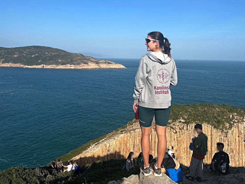 Girl in KI hoodie standing on a rock infront of the ocean at UNESCO Global Geopark