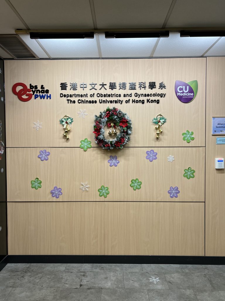 A wall at Prince of Wales Hospital with a sign of the Obstetrics and Gynaecology clinic with a Christmas reef and stick on snowflakes