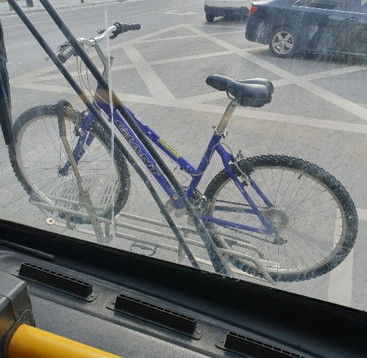 Bike attached to the front of a bus as viewed from the inside of the bus