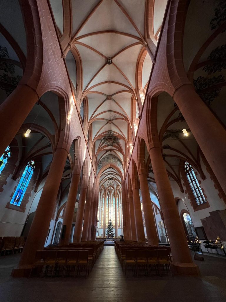 photo depicting the inside of a gothic style church with the characteristic arches and pillars. The color pallet of the church is mainly white and brick red.