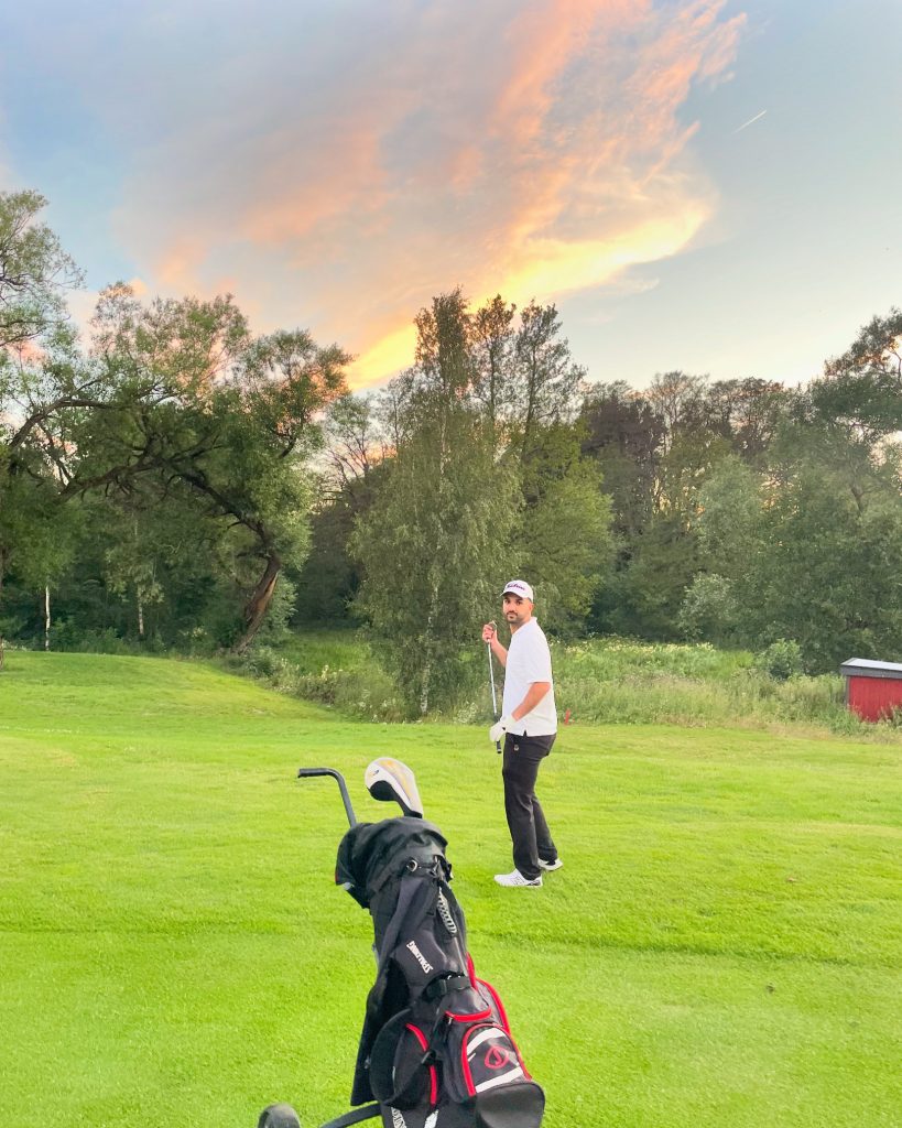 Man på golfbana bredvid en golfbag.