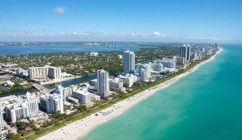 Foto över lägenheter vid stranden i Florida till vänster och havet bredvid till höger.
