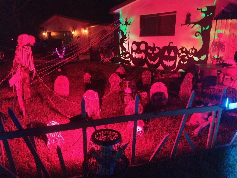 Trädgård halloween dekorerad med gravar och dylikt med ett rött sken.