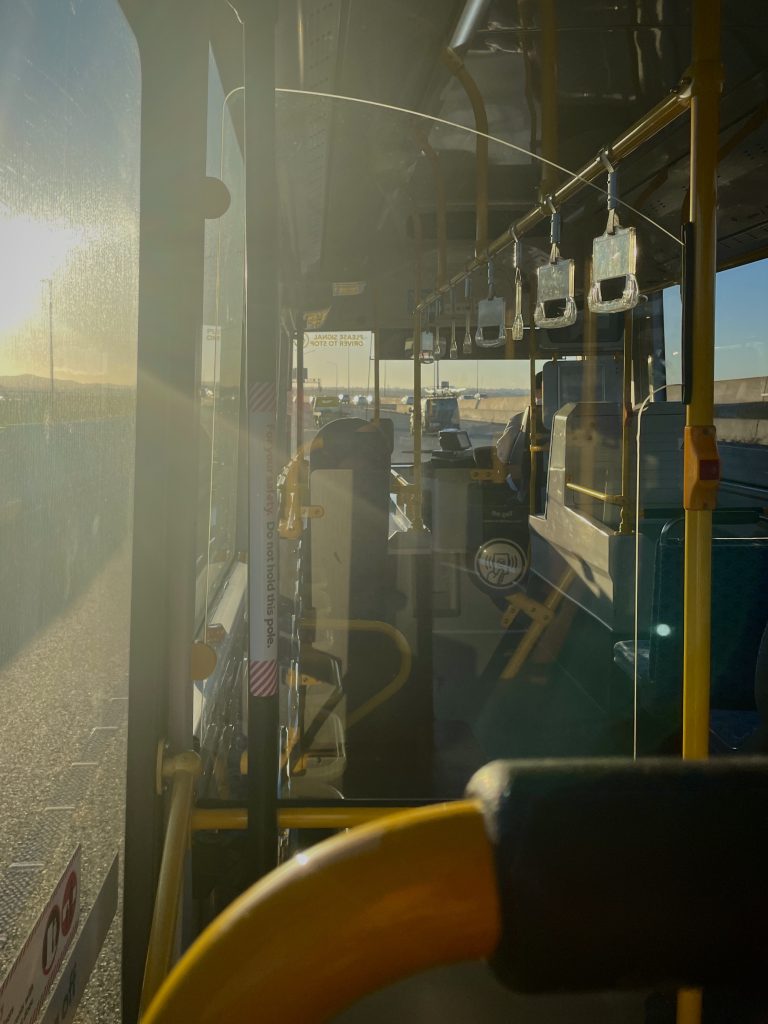 Sitting inside of a bus with sun set rays peeking through the window