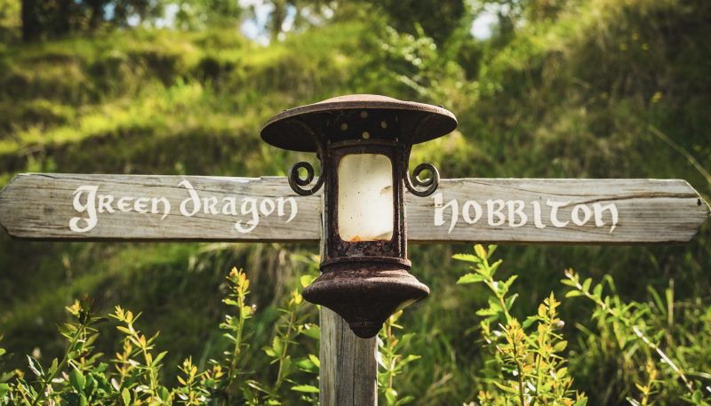 a wooden sign pointing to Dragon in and Hobbiton in the Shire