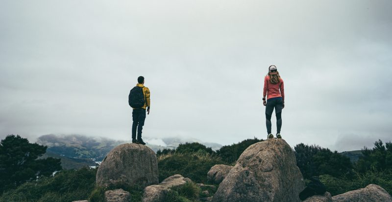 two people looking towards the mist standing on two boulders