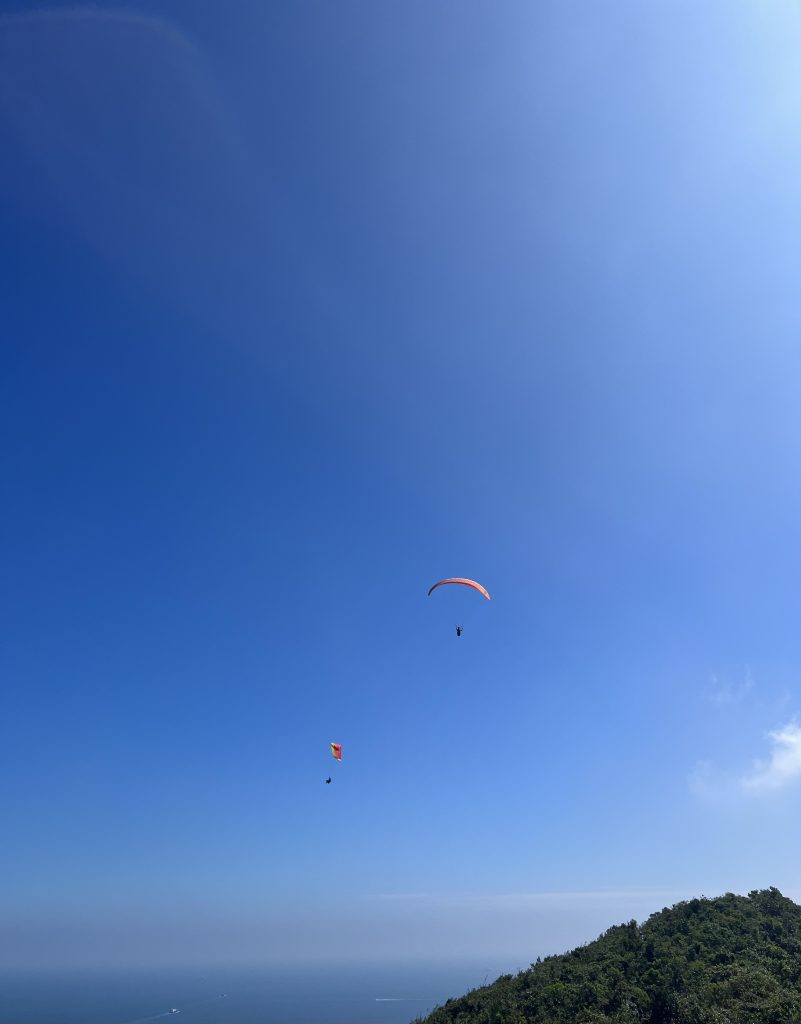 Two paragliders over a mountain and ocean.