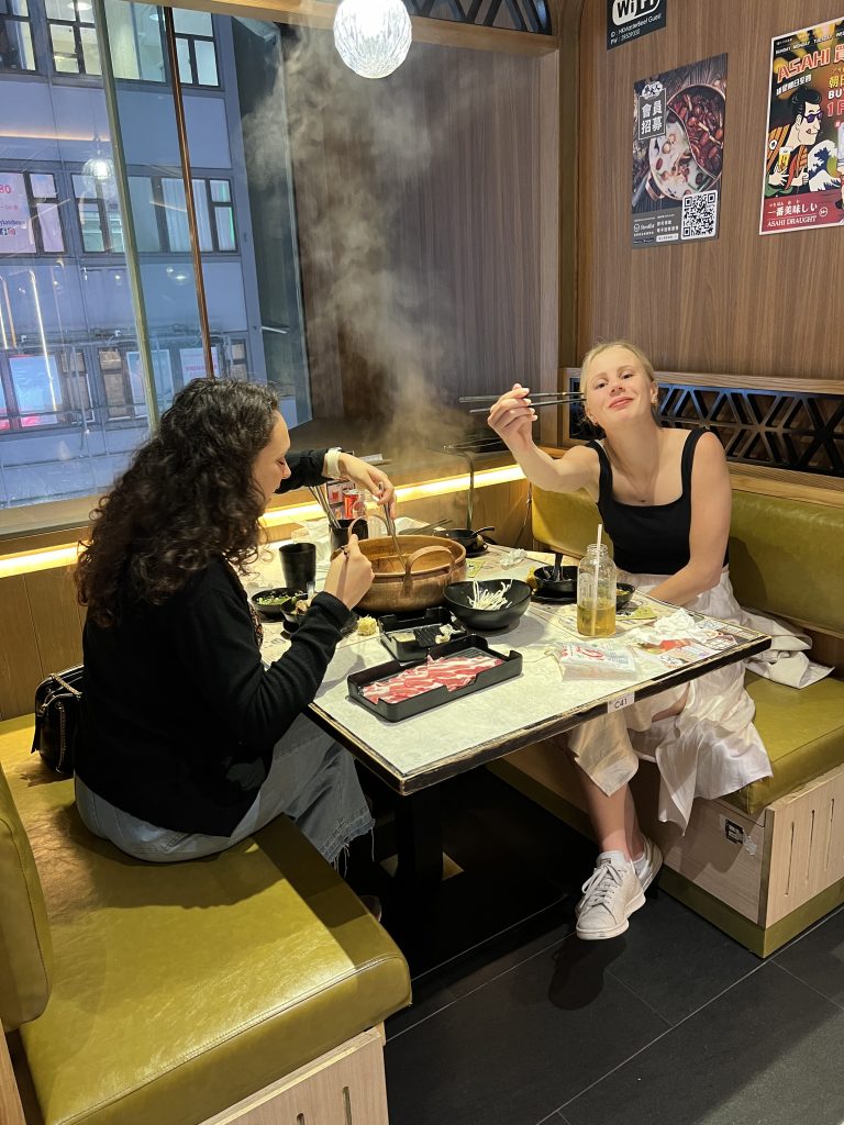 Two girls sitting in a booth and eating hot pot
