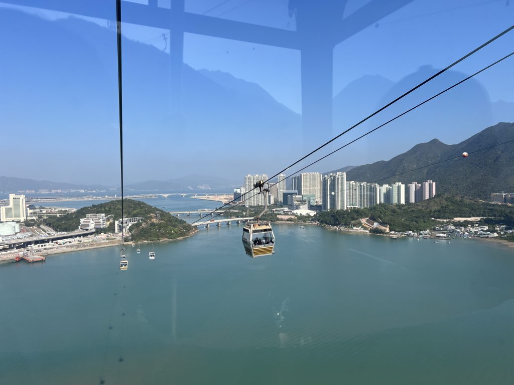 Cable cars over an ocean and a city in the background