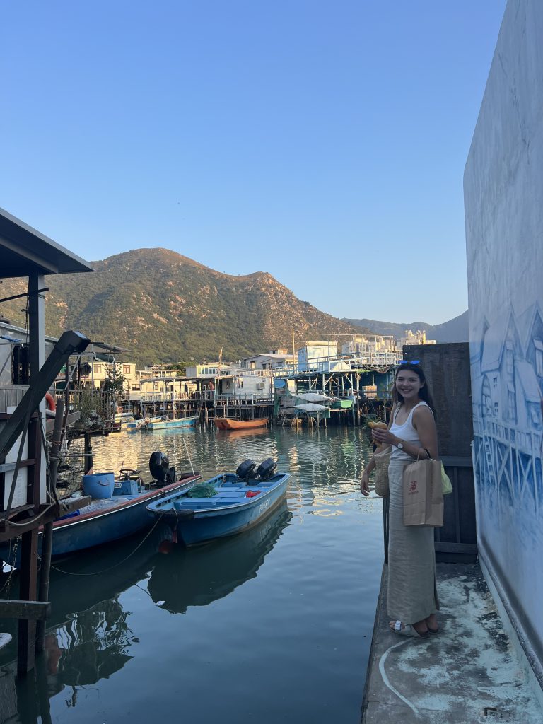Girl standing by the water and houses on stilts in Tai O