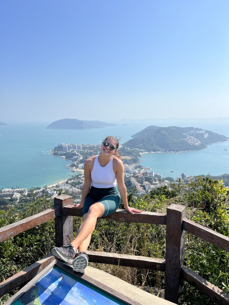 A girl posing on a look out point overlooking a city and the ocean