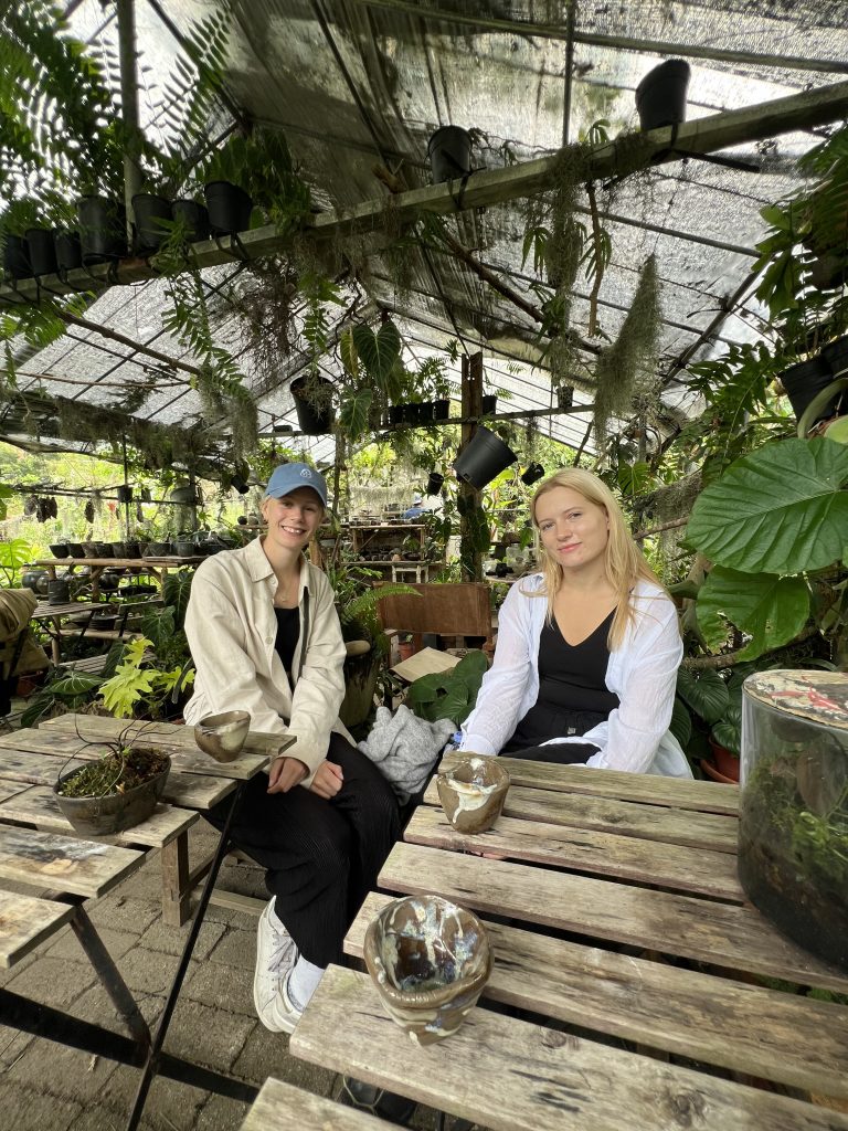 Two girls siting at an outdoor tea shop surrounded by greenery