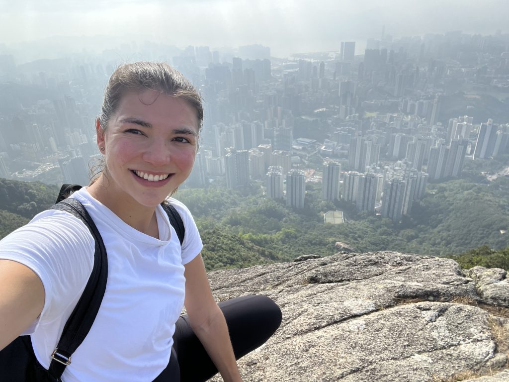 A girl sitting on a big rock overlooking the Hong Kong skyline