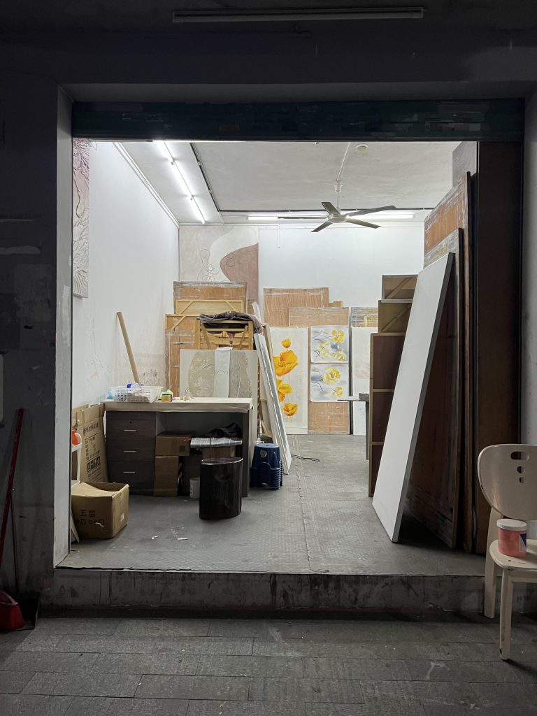 The inside of an art studio with boxes and paintings of flowers and abstract flowers. 