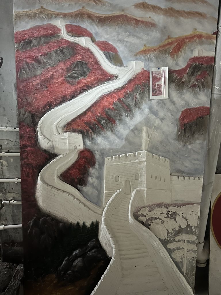An oil painting depicting the Great Wall of China with a red mountain.  