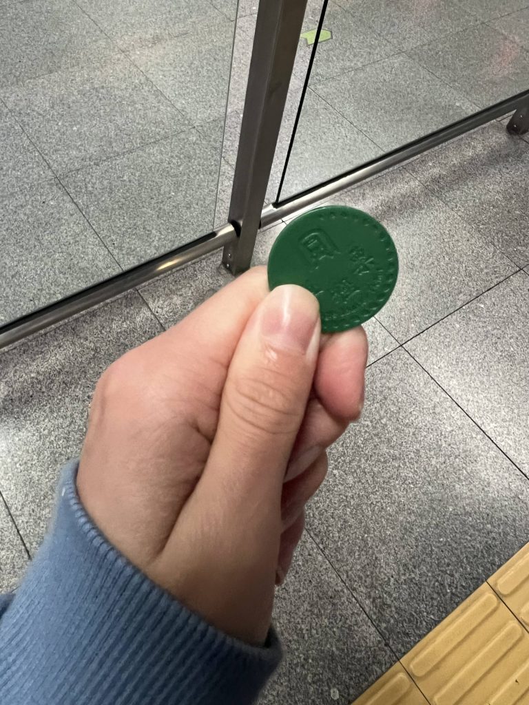 A hand holding onto a green coin.