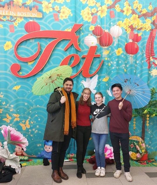Four people standing in front of a decorated wall smiling at the camera