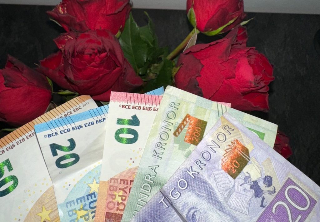 Euro sedlar och svenska kronors sedlar med rosor i bakgrunden