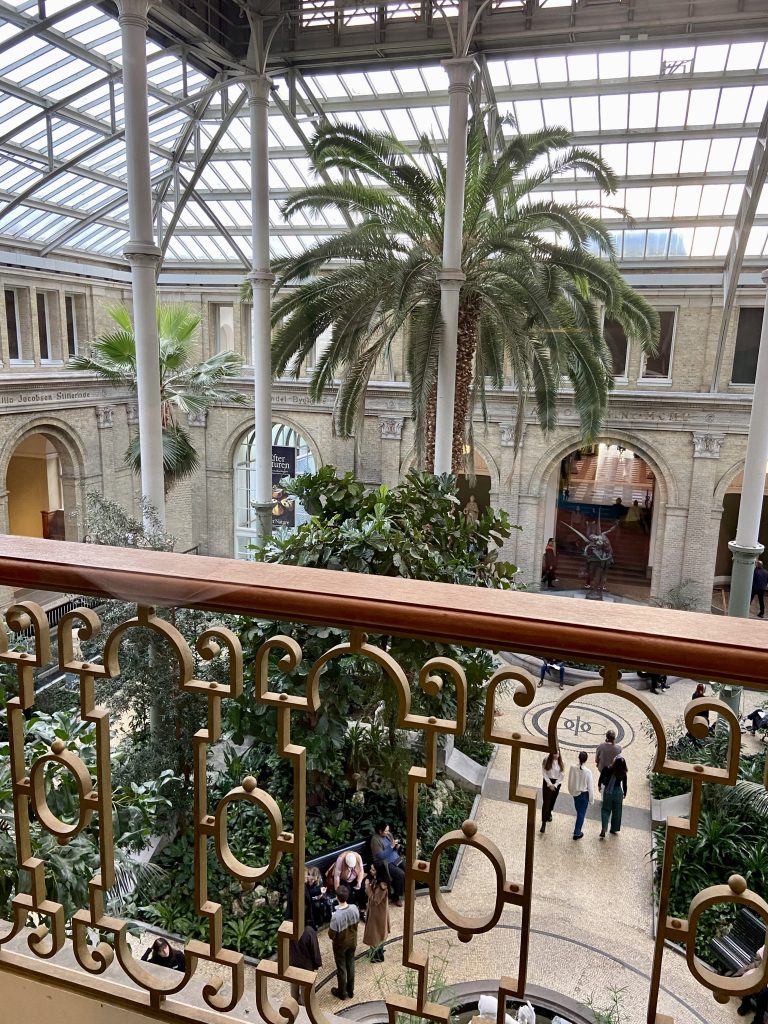 Utsikt över museumhall med palmer och grönska