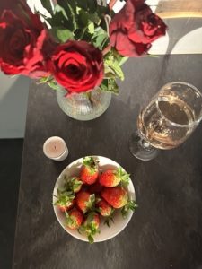 en bild på röda rosor, jordgubbar, ljus och läsk