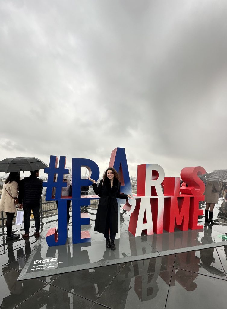 en bild på Sandra med texten (Paris je t'aime) med stora bokstäver i bakgrunden