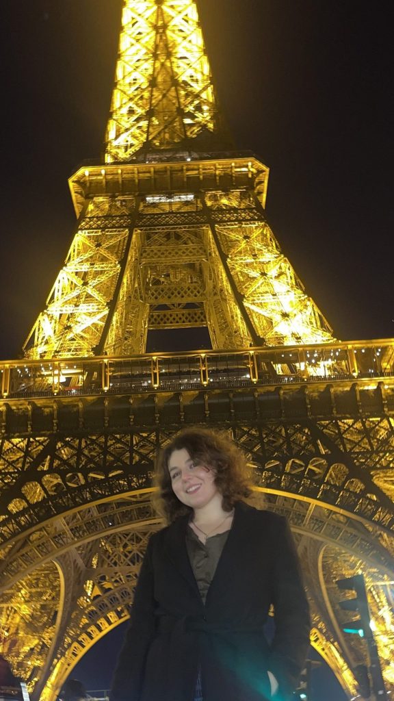 En bild på Sandra framför Eiffel Tornet på nattetid