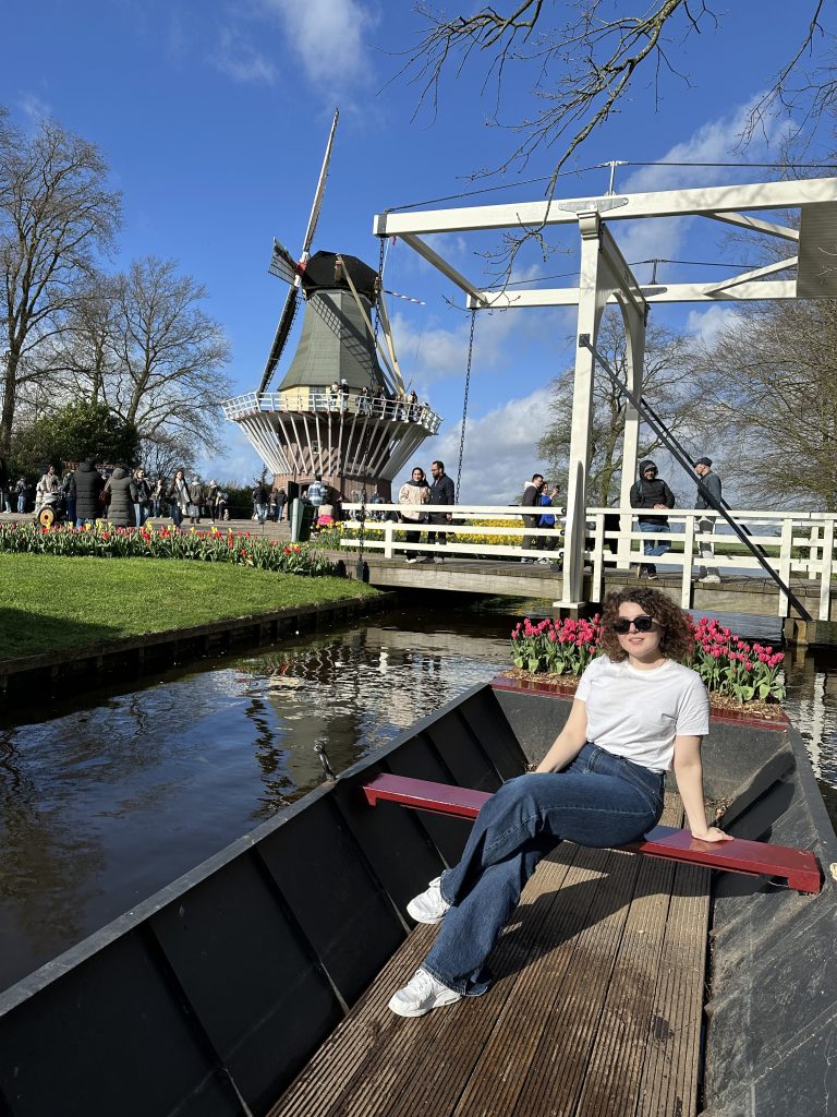 En bild på Sandra som sitter på en båt med tulpaner och en väderkvarn i bakgrunden