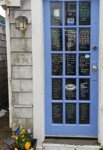 Blue door with many famous quotes written on the glass in the painted blue doorframe.