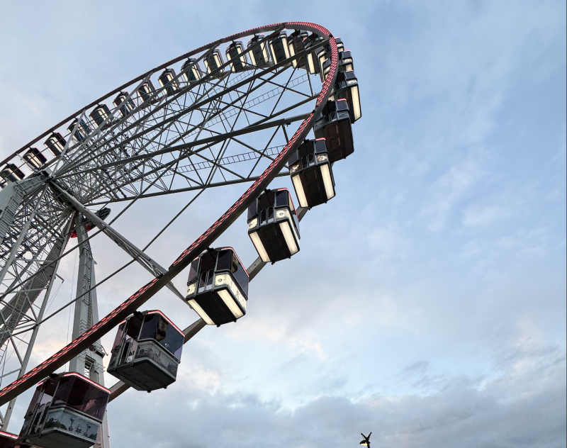 Ett Pariserhjul fotograferat underifrån. Blå himmel med moln i bakgrunden