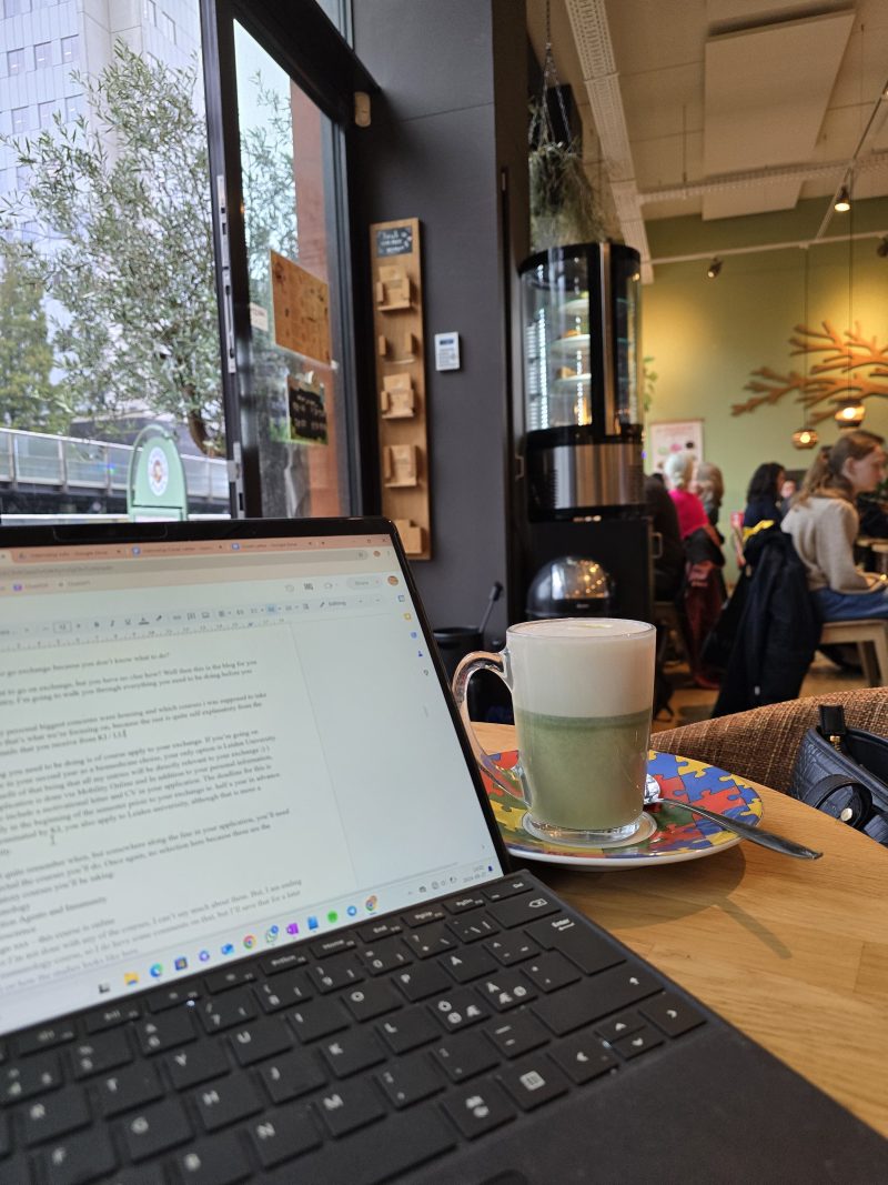 open laptop with a matcha latte on the side in busy café