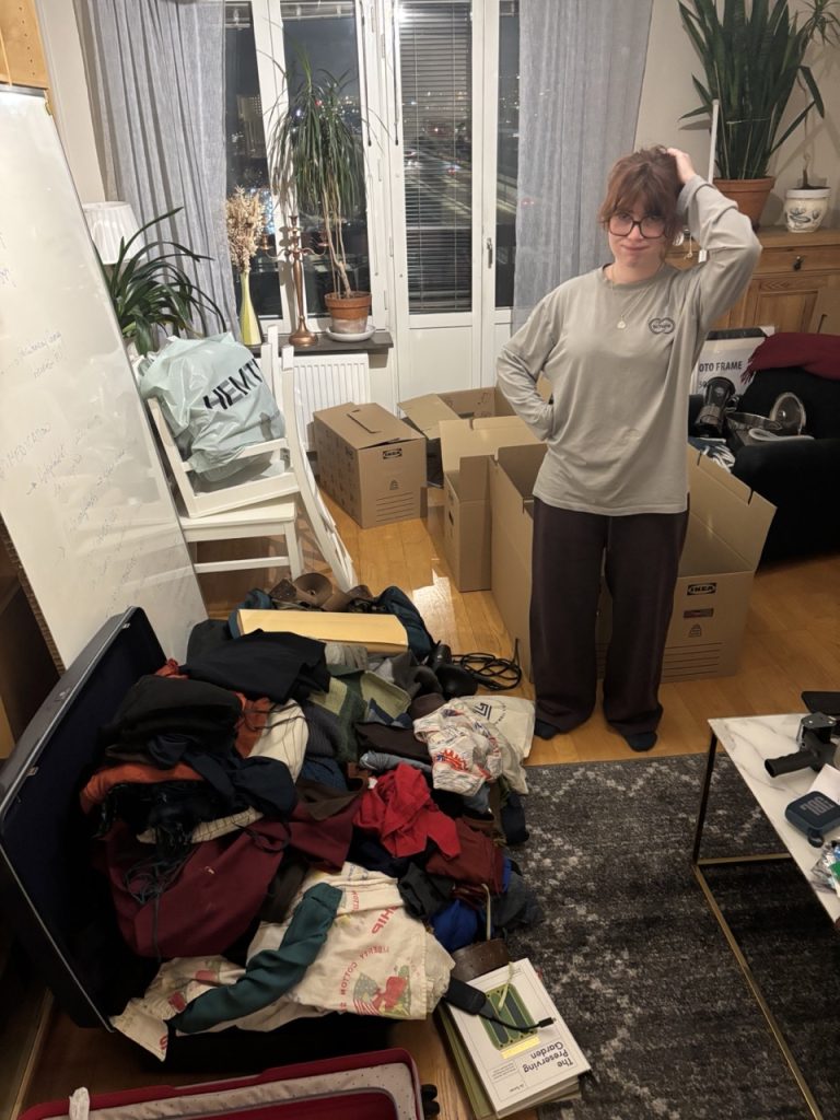 A student hopelessly stuffing her suitcase way past what is reasonable.