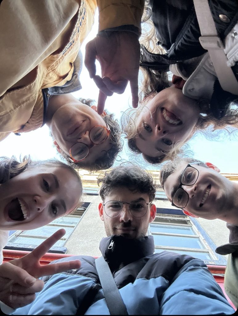 A group of students looking down on a camera, smiling.
