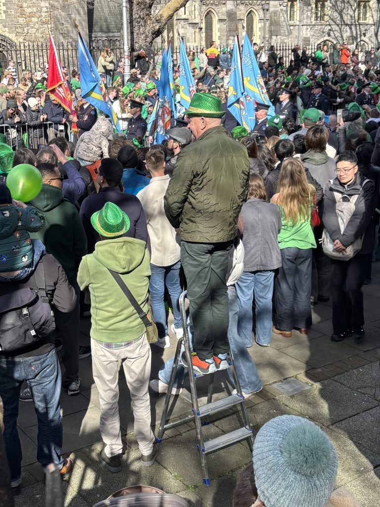 Man on a ladder looking over the rest of the crowd.