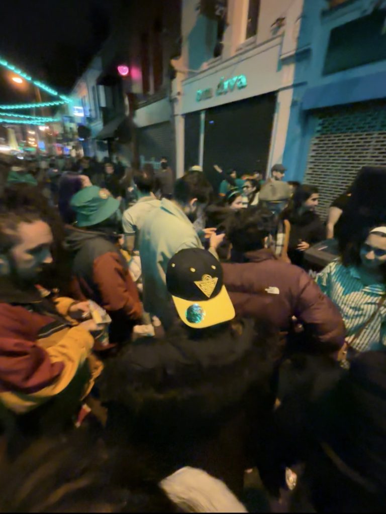 Group of people on the street around a large speaker.